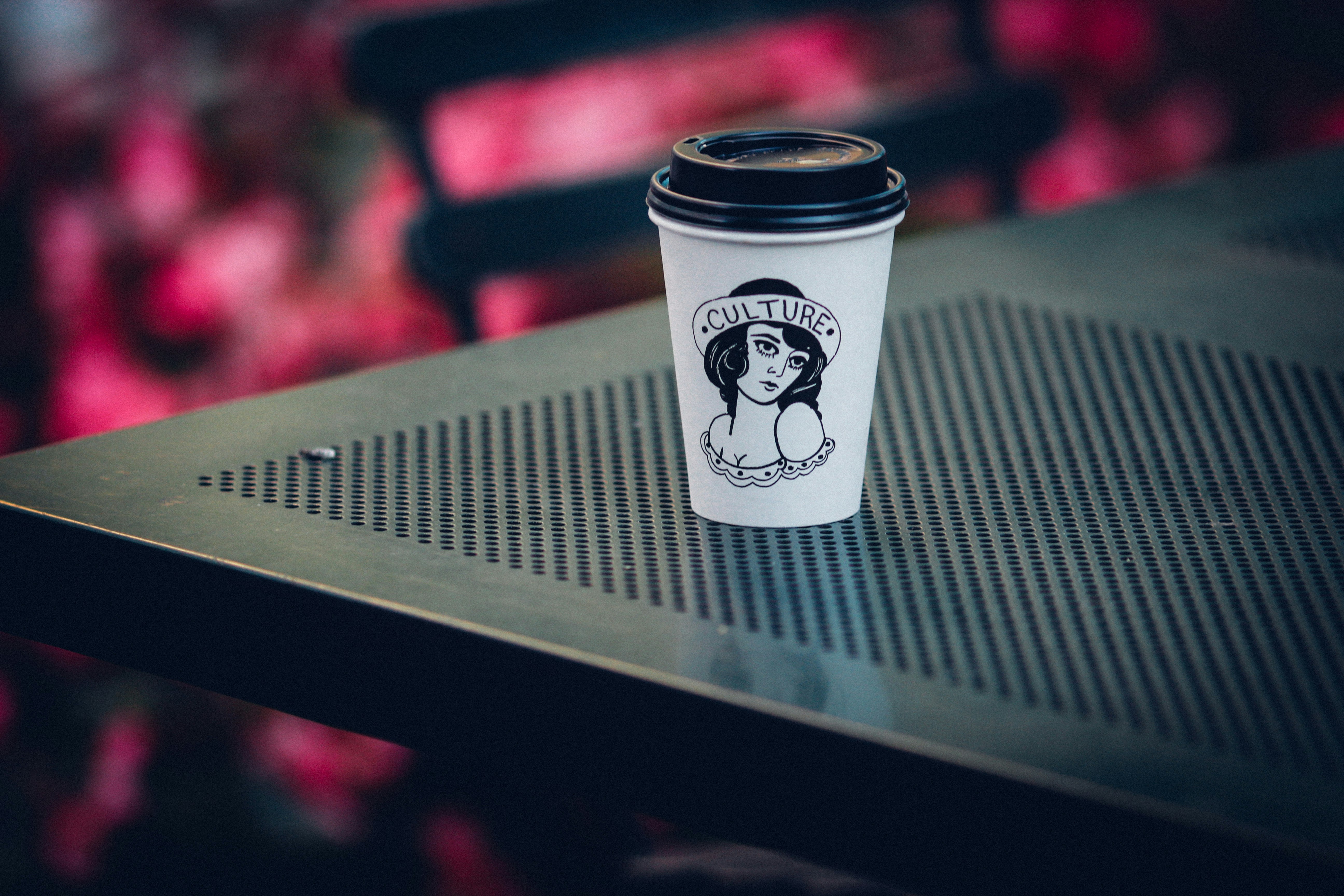 white and black disposable cup on gray metal table